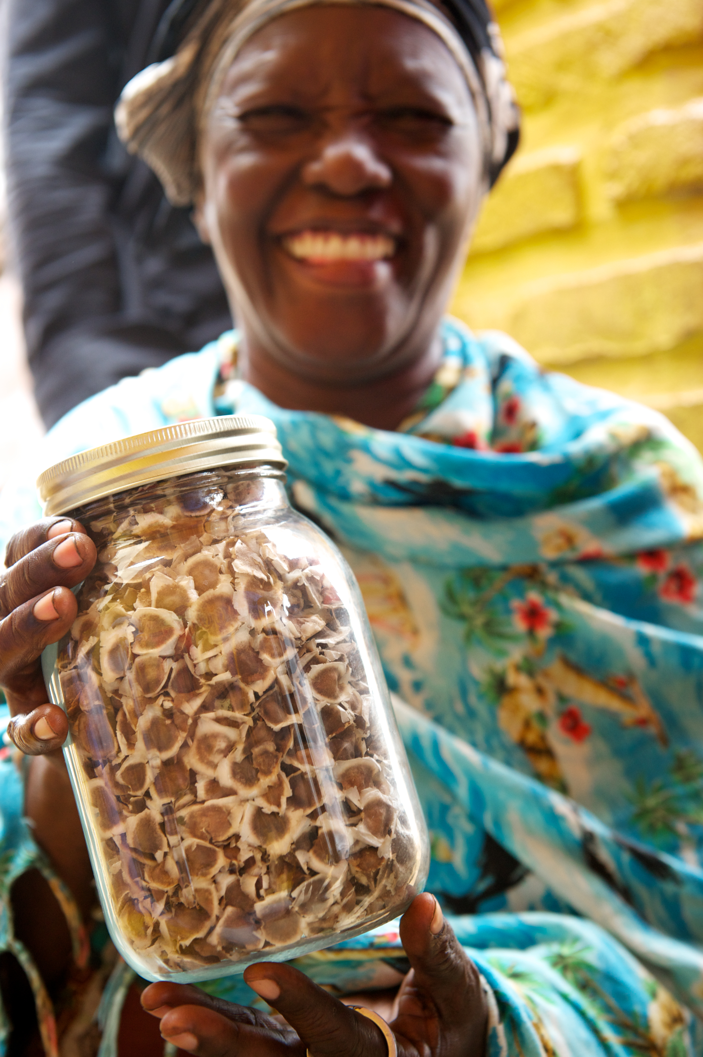 Excited woman holds jar of moringa seeds